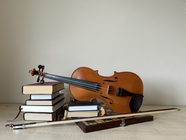 A vintage arrangement of chess pieces, old books, and a violin on the table in the minimalistic room.